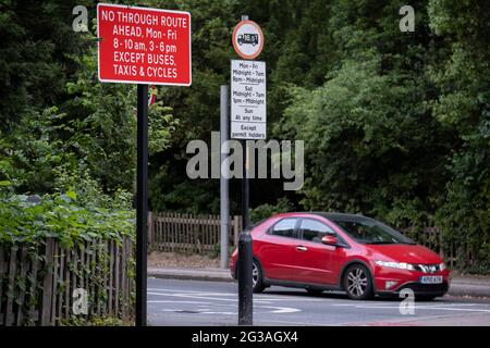 A car passes the signpost at the junction of the South Circular (A205) and College Road in Dulwich Village, warning motorists of the restrictions preventing traffic from passing through at morning and afternoon rush-hour times in the borough of Southwark, on 15th June 2021, in London, England. Stock Photo