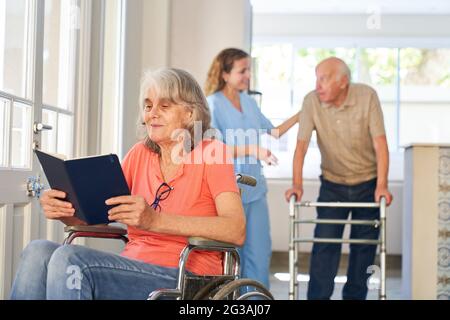 Senior patient in a wheelchair reads a book in the retirement home or rehab clinic