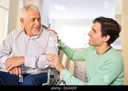 Caring man taking care of senior father in wheelchair in retirement home or at home Stock Photo
