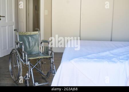 Empty wheelchair and empty bed in hospital symbolizing disability and healthcare Stock Photo