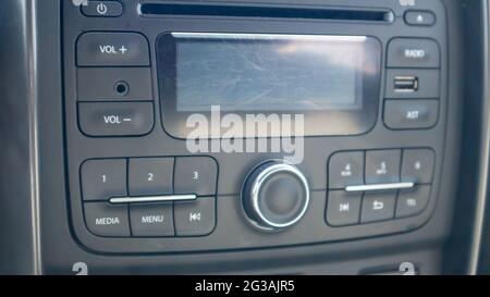 Established multimedia in the car. Close-up of the head unit and radio receiver with display inside the car. Dust and scratches are visible on the dev Stock Photo