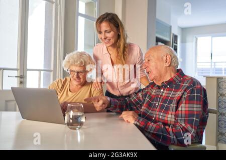 Curious senior couple with daughter on laptop computer while video chat in home Stock Photo