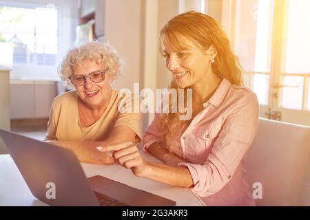 Daughter Helping Senior Woman Using Laptop Computer During Video Chat At Home Stock Photo