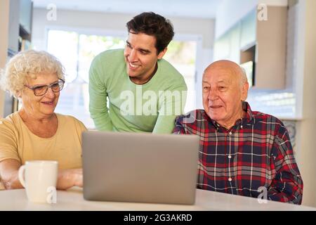 Senior couple enjoys studying in computer class together with their son at home Stock Photo