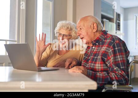 Happy senior couple on laptop computer making a video call with family at home Stock Photo
