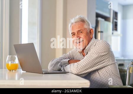 Happy retired senior using laptop computer at home enjoying the internet Stock Photo