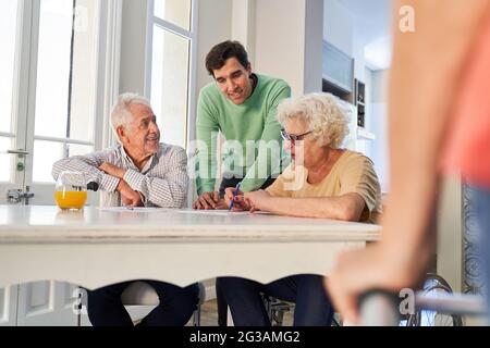 Young man and senior couple doing brain jogging or memory training against dementia Stock Photo
