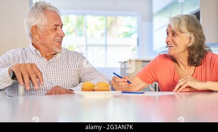 Happy senior retired couple solving puzzles at home as memory training Stock Photo