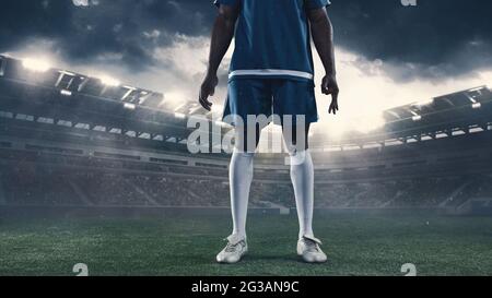Cropped portrait of male soccer, football player standing posing at the stadium before sport match on dark sky background. Collage Stock Photo