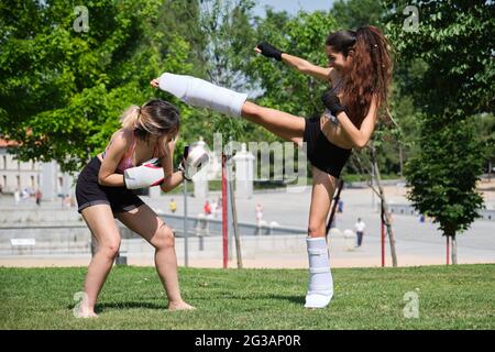 Two women practicing muay thai, boxing, kickboxing, in a park. Sport outdoors. Stock Photo