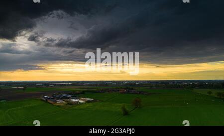 Aerial landscape of countryside with colorful storm clouds. Extreme thunderstorm over a farm and agricultural fields and road. High quality photo Stock Photo