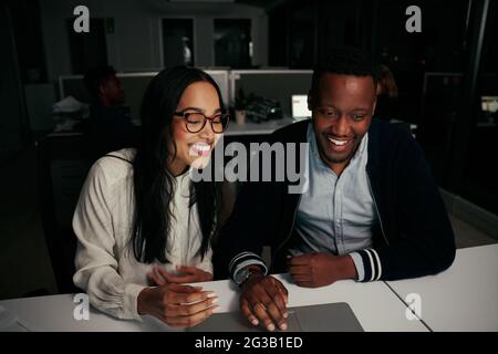 Happy young diverse business colleagues enjoying working together on laptop at desk in office Stock Photo