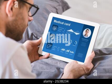 Young Man With Glasses Laying On Bed At Home Using Digital Tablet Reading Medical Card Checking His Health Condition Or Reading Anamnesis Online M Stock Photo Alamy