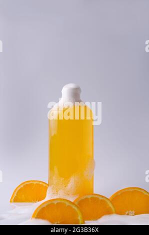 Shampoo, shower gel, orange liquid soap with natural ingredients in a transparent bottle on a light background in foam with orange pieces Stock Photo