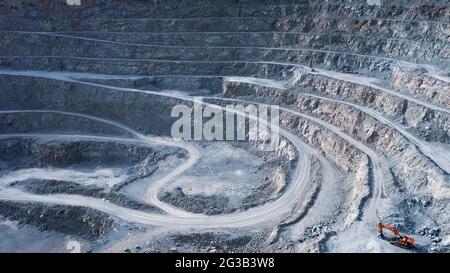 Red excavator machine on a terrace of gravel quarry, aerial view Stock Photo