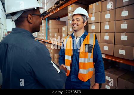 Happy technicians greeting each others at industrial storehouse Stock Photo