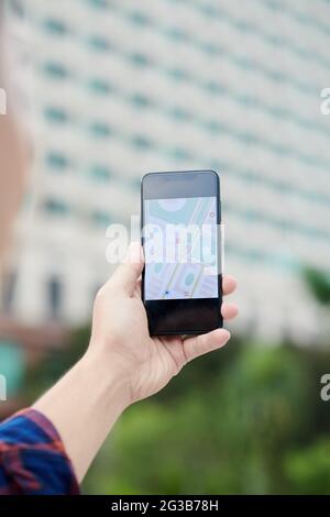 Close-up of unrecognizable man using GPS navigation on smartphone against modern building while searching for place Stock Photo