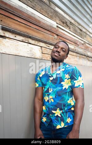 Young smiling ?exican male standing outdoors leaning on the wall Stock Photo