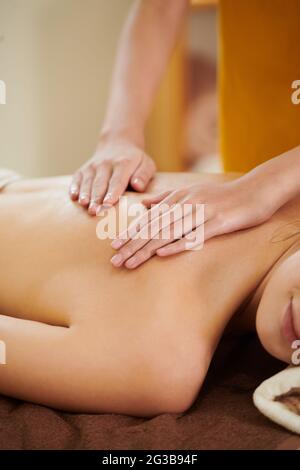 Close-up of woman lying on sofa while therapist massaging her back Stock Photo