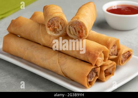 Plate with crispy deep fried Vietnamese egg rolls and a halved one on top Stock Photo