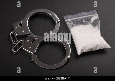drug punishment, handcuffs and white cocaine powder top view. Stock Photo
