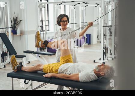 Man performing the knee flexion assisted by a physiatrist Stock Photo