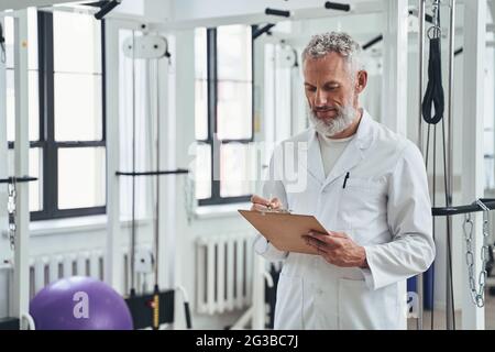 Professional kinesiologist taking notes during the physiotherapy session Stock Photo