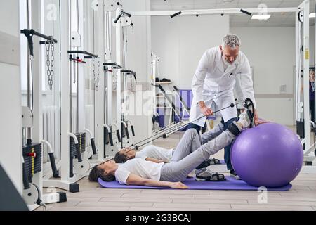 Patient performing a strength training exercise assisted by a kinesiologist Stock Photo