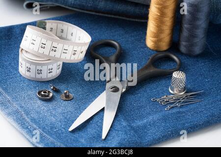Sewing Tools And Blue Jeans Fabric On White Table Close Up. Stock Photo