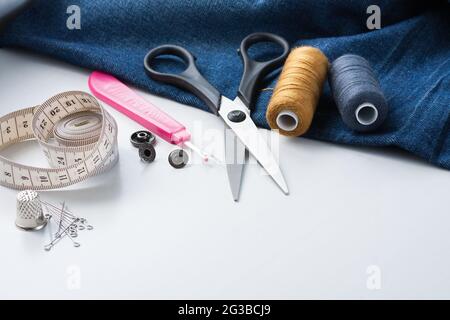 Sewing Tools And Jeans Fabric On White Table With Copyspace. Stock Photo
