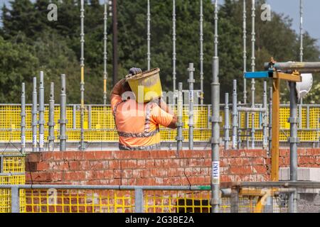 House building stages of construction man carrying mortar bucket; Farington Mews Beat the Stamp Duty Deadline - Keepmoat homes development site bricklayer in Chorley. Builders & bricklayers start construction on this large new housing estate. Stock Photo