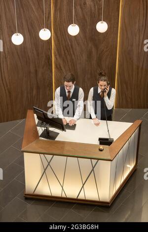 Young hotel reception managers in uniform working by counter Stock Photo
