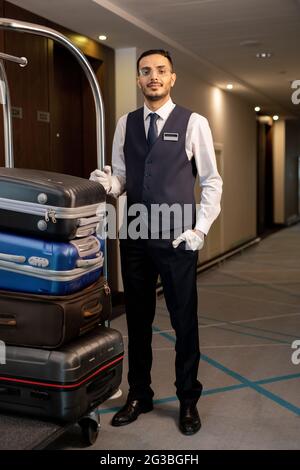 Young elegant porter standing in corridor of hotel Stock Photo
