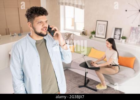 Happy young man talking on smartphone in home environment Stock Photo