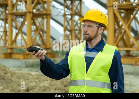 Young builder in uniform and hardhat working at construction site Stock Photo