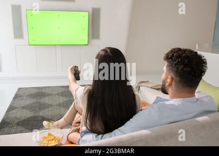 Young couple watching tv while relaxing on couch in living-room Stock Photo