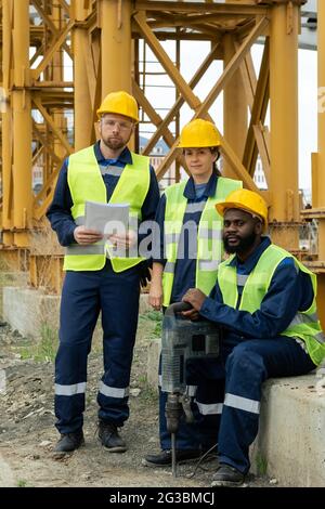 Three intercultural builders in uniform on construction site Stock Photo