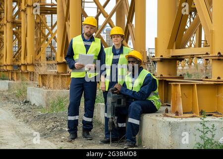 Group of young contemporary builders in workwear working outdoors Stock Photo