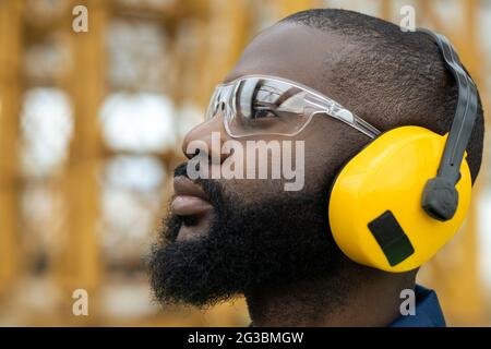 Profile of African builder in protective eyewear and earphones Stock Photo