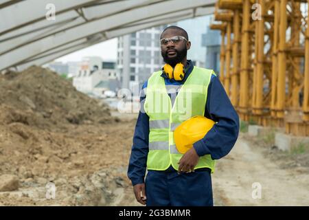 Young engineer in uniform holding protective helmet Stock Photo