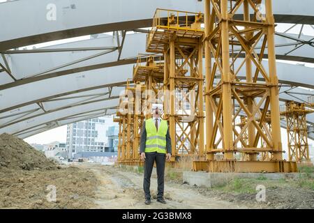Young builder in formalwear and vr headset standing on construction site Stock Photo