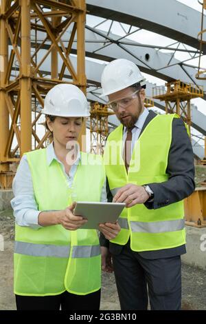 Small group of engineers scrolling through data on tablet screen Stock Photo