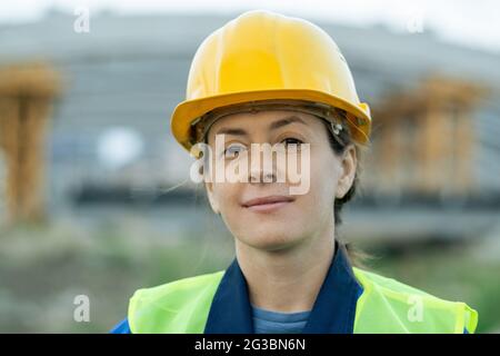Successful female builder in protective helmet looking at you Stock Photo