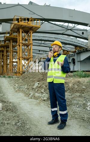 Male engineer in workwear communicating on walkie-talkie Stock Photo
