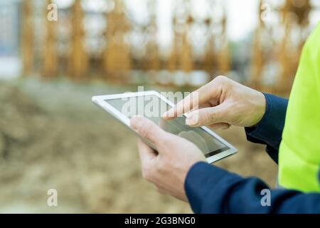 Hand of engineer pointing at sketch of building on screen of tablet Stock Photo