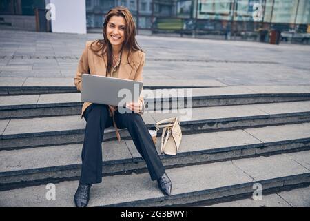 Good-looking female entrepreneur sitting on the stairs Stock Photo
