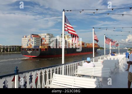 Massive carge ship passing a Paddlesteamer on the Savannah River USA Stock Photo