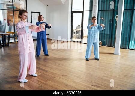 Three people involved in moving meditation in spacious room Stock Photo