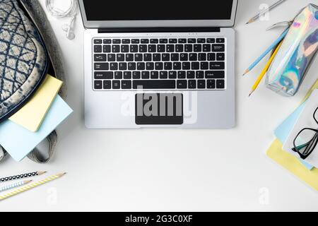 Flat lay top view modern laptop with backpack and stationery on white table Stock Photo