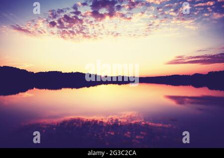 Scenic golden sunset over calm water, color toning applied. Stock Photo